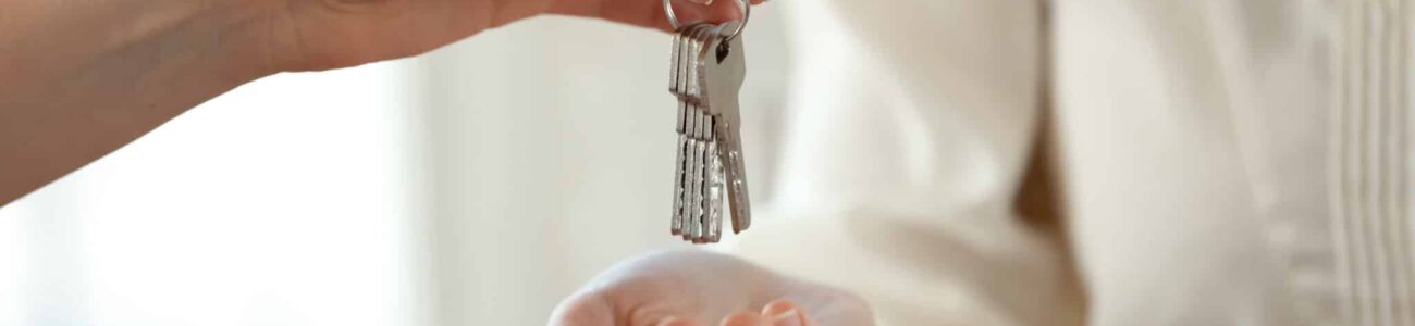 Close up young female realtor giving keys to happy buyer. Guest Adom, conciergerie locative, s'occupe de votre Airbnb