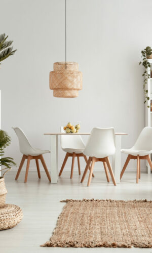 Plants on shelves and rug in white apartment interior with chairs at dining table under lamp. Real photo Plants on shelves and rug in white apartment interior with chairs at dining table under lamp. Real photo