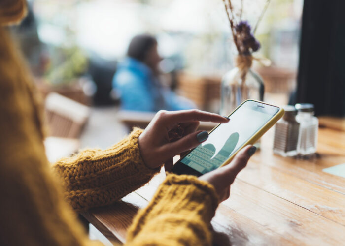 girl hold in hands yellow empty screen mobile phone close up, person type message on smartphone in sun cafe, relax tourist travels planning trip, hipster enjoy journey in cityscape, lifestyle holiday concept, internet online
